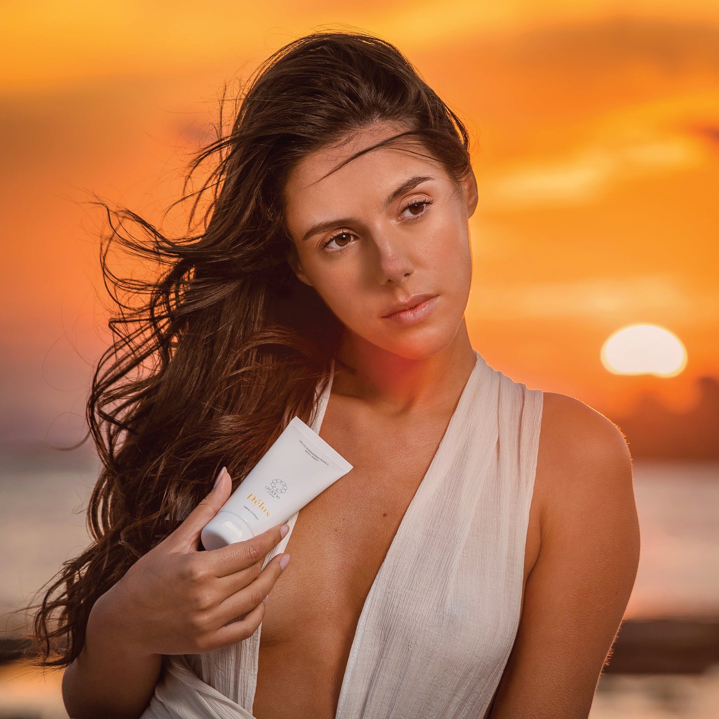 A woman holds he Délos Shimmering Pearls Body Wash.